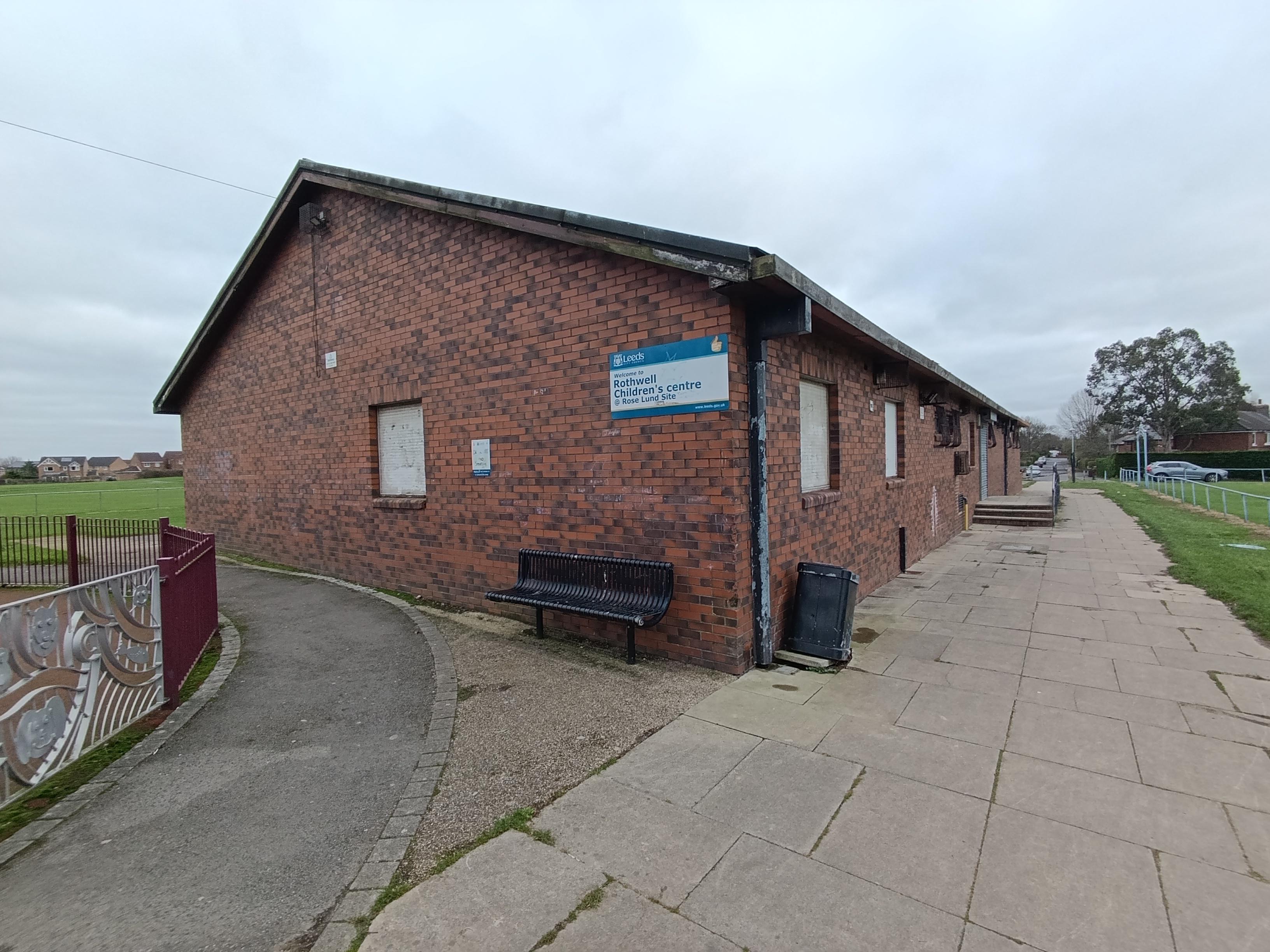 image showing a former children's centre building, a single-storey, brick building with wide pavement to the front and surrounded by grass to the front and rear